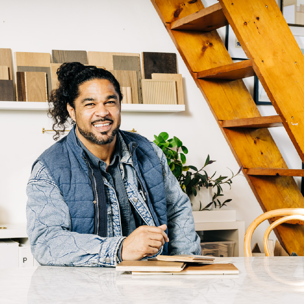 Sebastian Clovis, smiling while sitting at table inside a beautifully designed home.