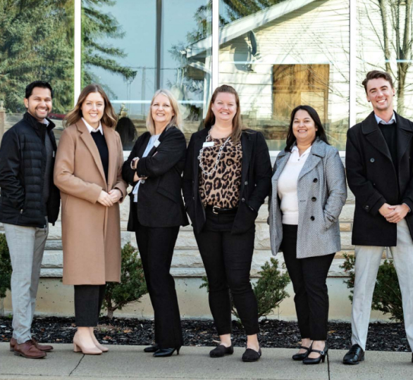 A group of 6 Meridian employees gather outside in front of a branch 