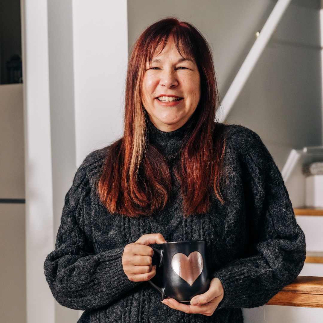 Meridian Member, Kelly Waterhouse, smiling and holding a black coffee mug