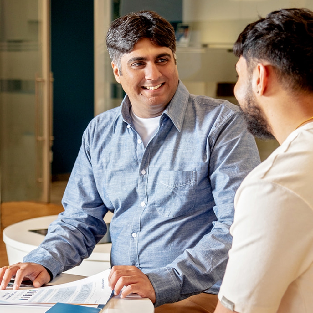 A light skinned, male, Meridian advisor, talking with a client and sharing reports. 