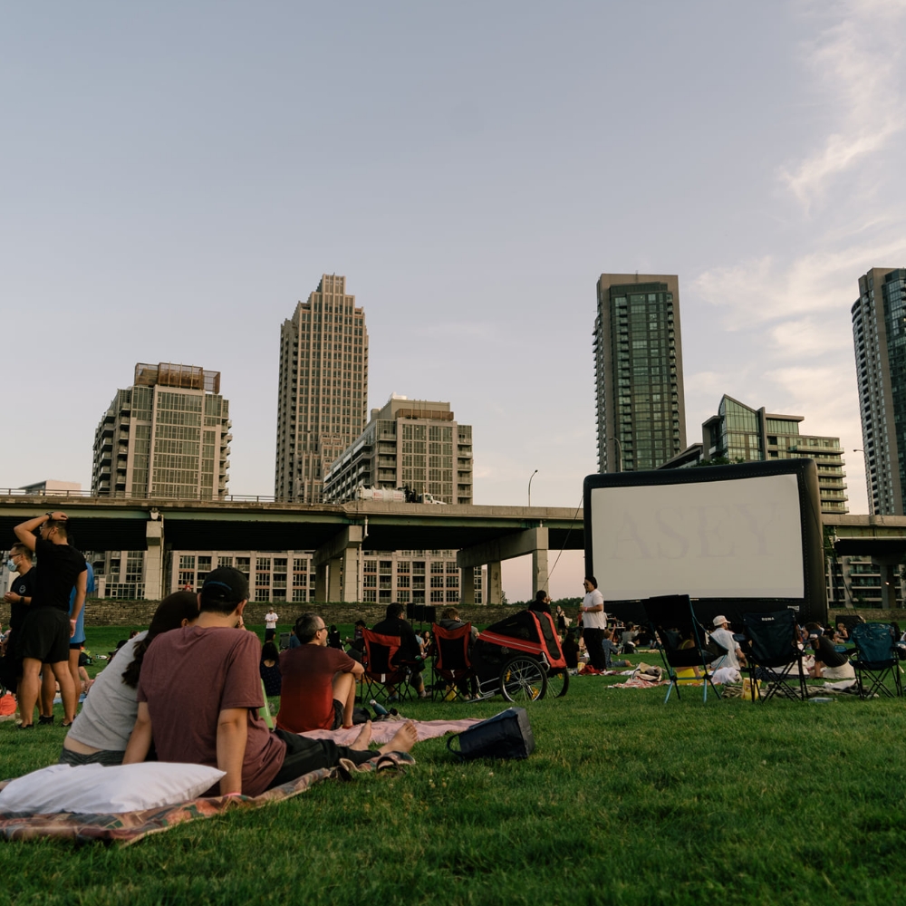 People in a Toronto urban park in front of a large inflatable movie screen.