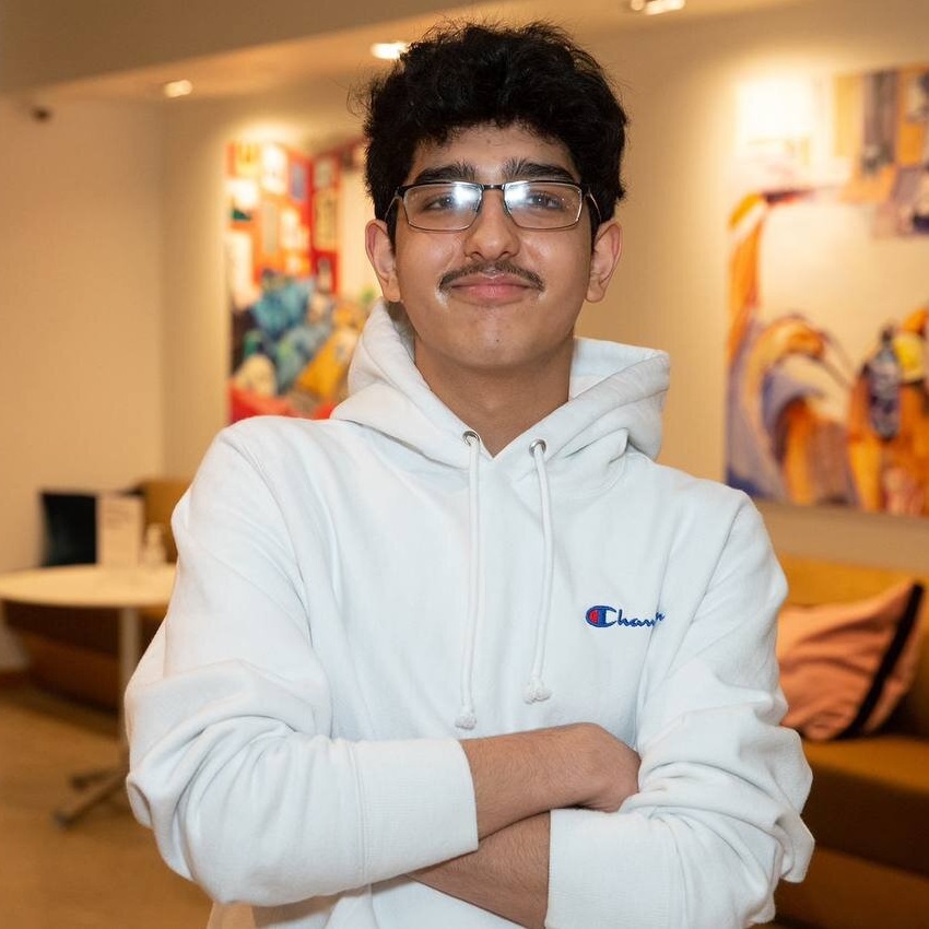 Yogya Kalra, 2023 scholarship recipient stands, arms folded, smiling. 