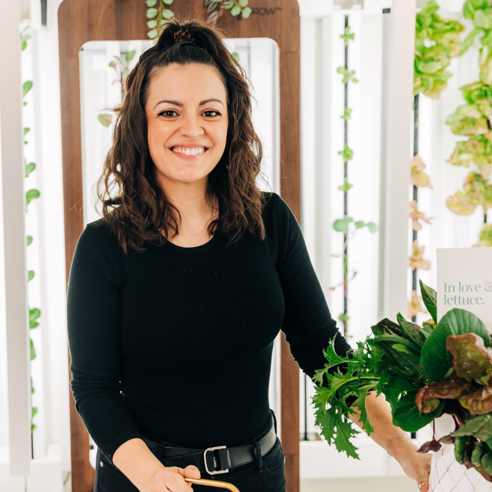 Staff Member at Mon Petit Chou, smiles, next to a floral arrangement