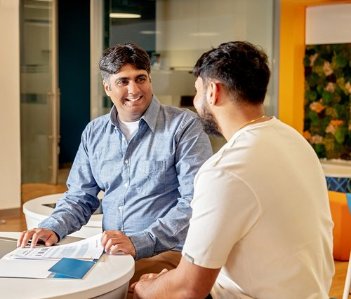 Two employees siting together, looking at paperwork 