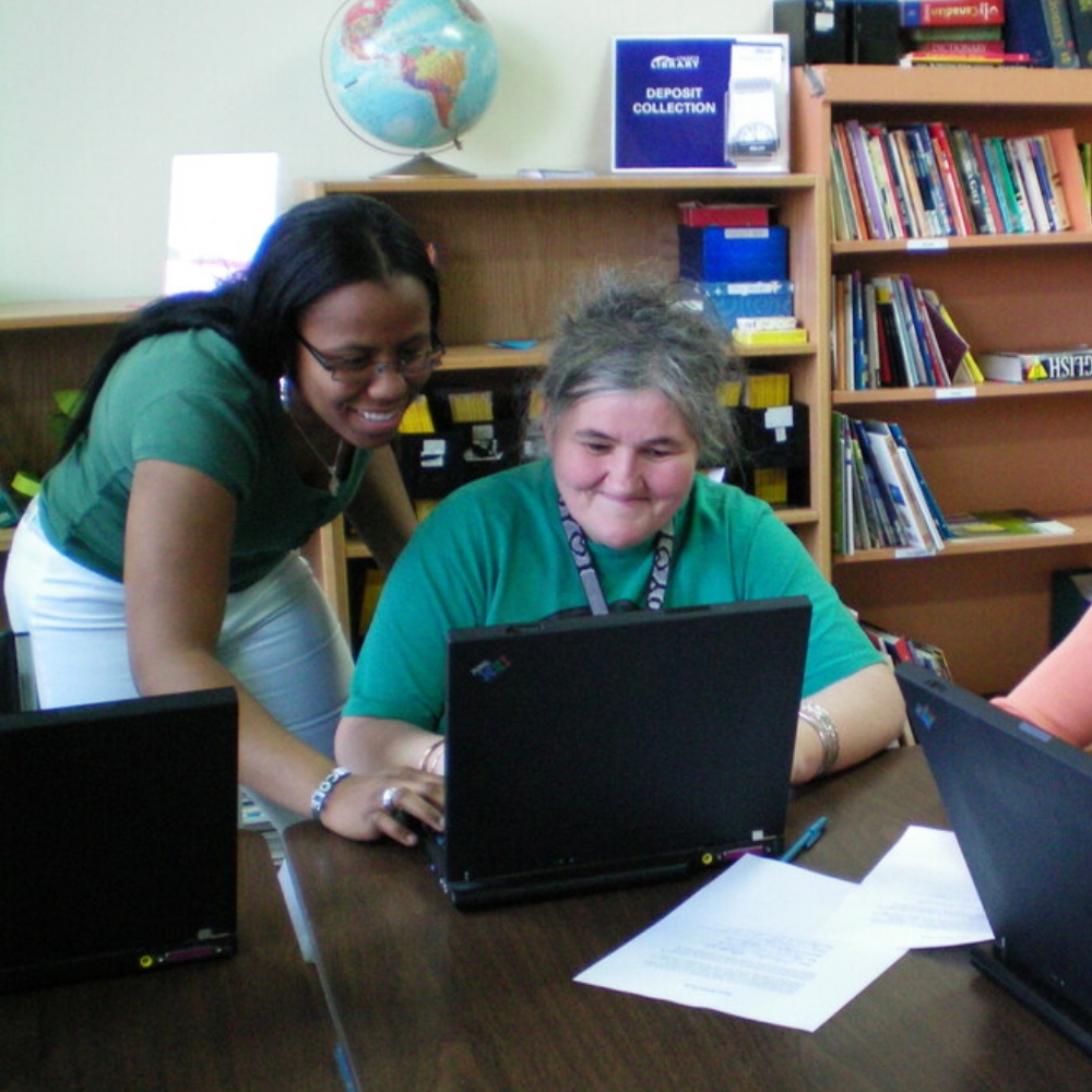 Two smiling women looking at a laptop computer.