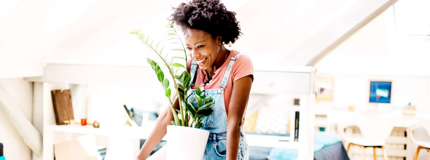 Happy woman is holding a potted plant