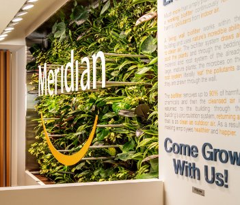 A living wall of plants with the Meridian logo at a corporate office 