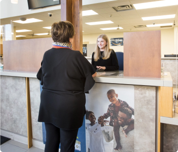 A Meridian employee behind the counter in a branch speaking with a co-worker 